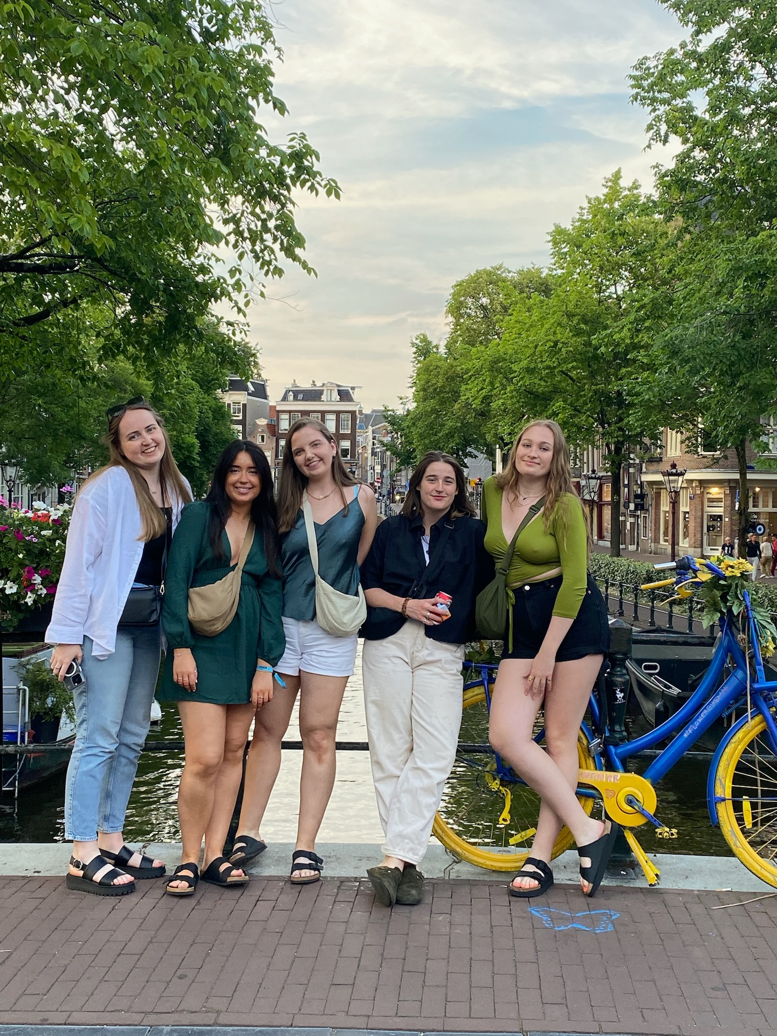 A group of girls posing on a bridge over a canal in Amsterdam.