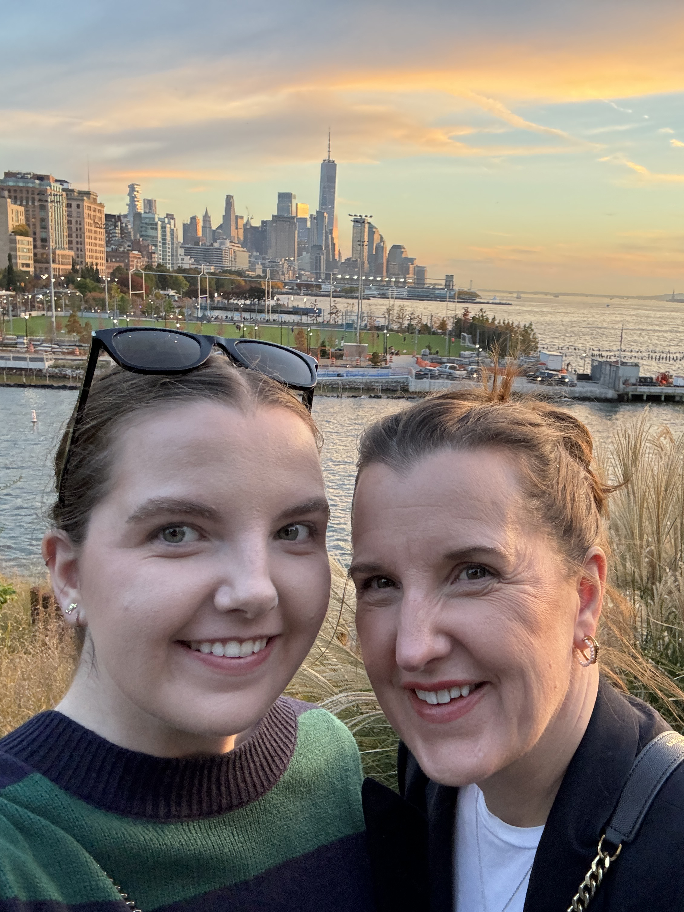 A mother and daughter taking a selfie with the sunset in the background.